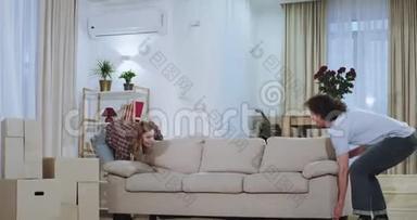 在一个宽敞的客厅里，有魅力的夫妇在客厅里拿着一张大沙发，在一个新的房间里享受时光。